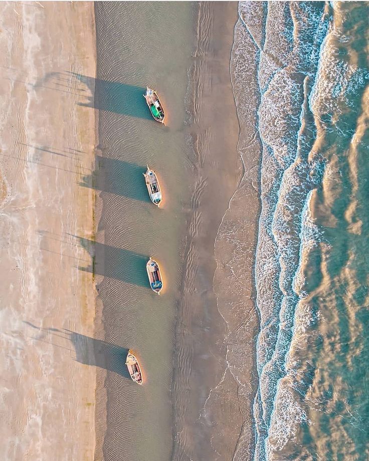 Aerial view of fishing boats lined along the shoreline at Mandvi Beach in Kutch, Gujarat, with waves from the Arabian Sea.